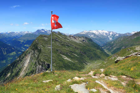 Swiss flag on a background of mountain valleyの写真素材