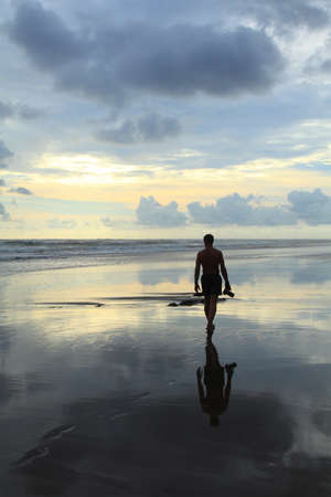 photographer with a camera walks along on the beach during an outflowの写真素材