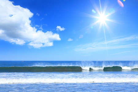 sea surf at the pacific ocean coaston a background of the sun and blue skyの写真素材
