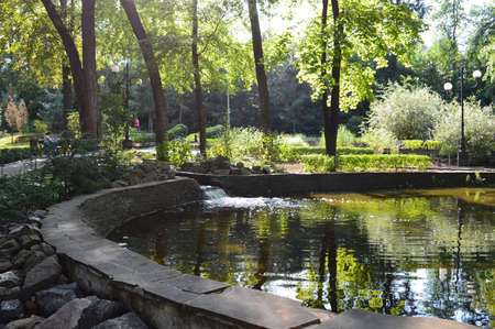 Donetsk, Shcherbakov Park, Ukraine-June 2020, an artificial pond with a waterfall in the summer in a deserted Park among trees and stonesのeditorial素材