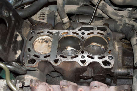A three-cylinder internal combustion engine with the block head removed stands on the car