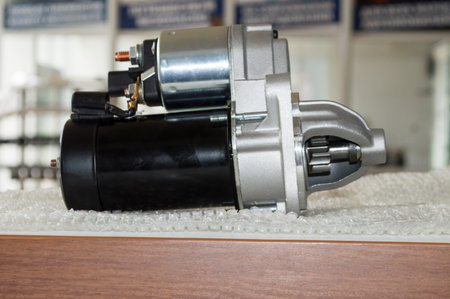 Side view of the new starter that lies on the table in the auto repair shop