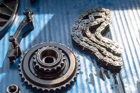 The elements of the chain drive of an automobile engine lie on a blue desktop in an auto repair shop