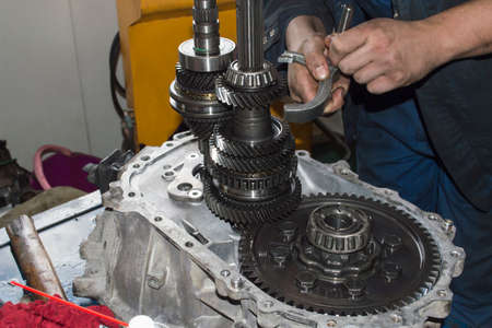 A mechanic checks the gearshift fork of a mechanical transmission with his hands in an auto repair...