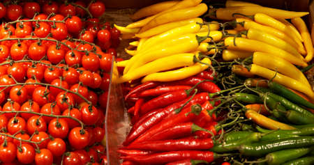 Piles of fresh tomatoes and peppers for saleの写真素材