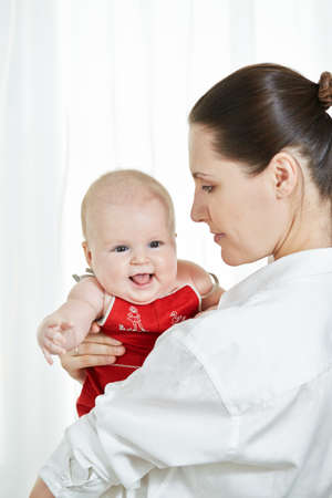 Mother with her happy child on arms on white backgroundの写真素材