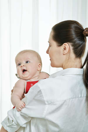 Mother with her child on arms on white backgroundの写真素材