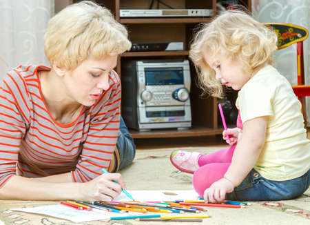 Mother with a little daughter draw pencilsの写真素材