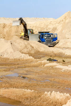 Excavator Loading Dumper Truck at Construction Siteの写真素材