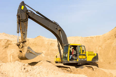 Working Yellow Excavator at Construction Siteの写真素材