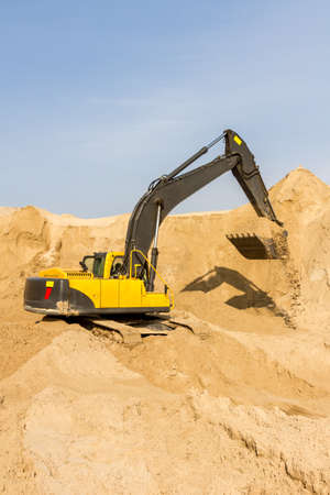 Working Yellow Excavator at Construction Siteの写真素材