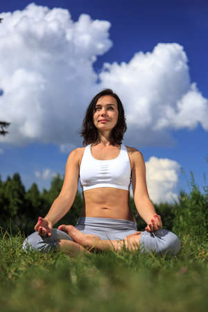 girl doing yoga outdoor with open eyes and smiling, verticalの写真素材