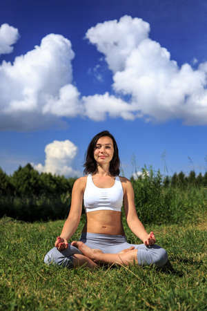 girl doing yoga outdoor looking in camera and smiling, verticalの写真素材