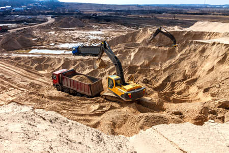 Excavator Loading Dumper Truck at Construction Siteの写真素材