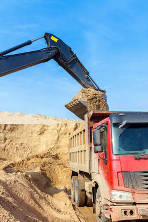 Excavator Loading Dumper Truck at Construction Siteの写真素材