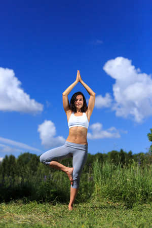 girl doing yoga outdoor with open eyes and smiling, verticalの写真素材