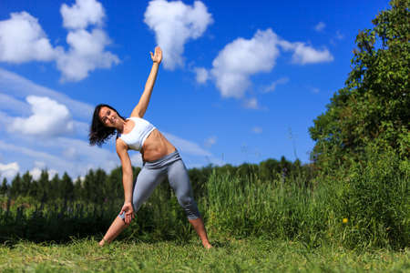 girl doing yoga outdoor looking in camera and smiling, ladscapeの写真素材