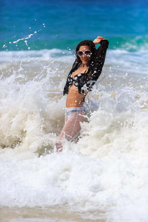 Young Beautiful Woman playing in waves on beachの写真素材