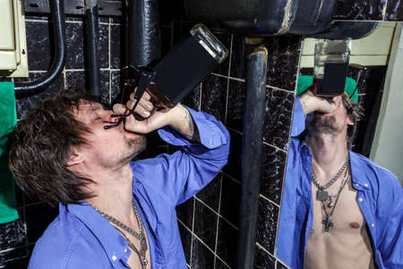 Drunk Man is standing in a toilet and drink whiskey  Color imageの写真素材
