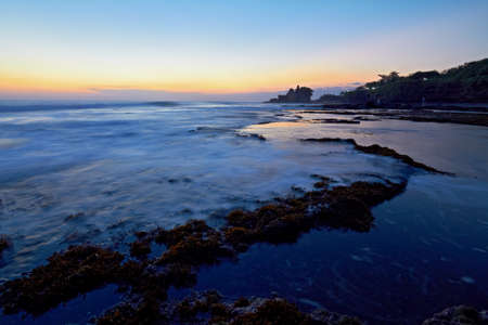 Tanah Lot Temple and ocean waves at sunset, Bali, Indonesiaの写真素材