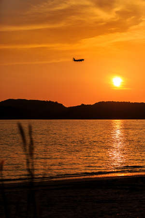 Silhouette of Passenger Airplane Landing at sunset above the sea