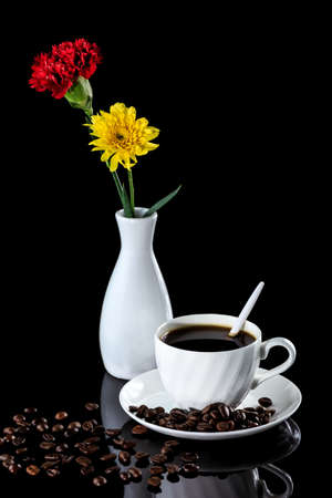 Composition with cup of coffee, yellow chrysanthemum and carnation on a black reflective background. Studio shotの写真素材