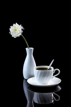 Composition with cup of coffee and white chrysanthemum on a black reflective background. Studio shotの写真素材