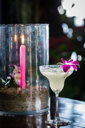 Composition with margarita cocktail, orchid flower and burning candle on the blurred backgroundの写真素材