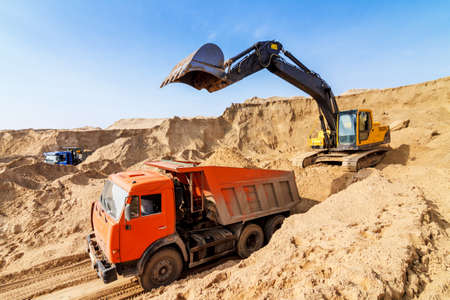 Excavator Loading Dumper Truck at Construction Siteの写真素材