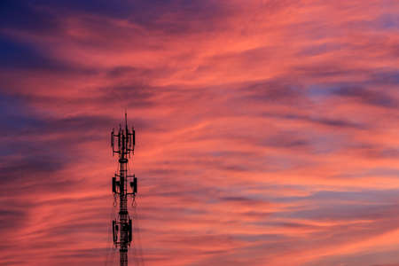 Silhouette signal antenna tower at beautiful sunset sky background