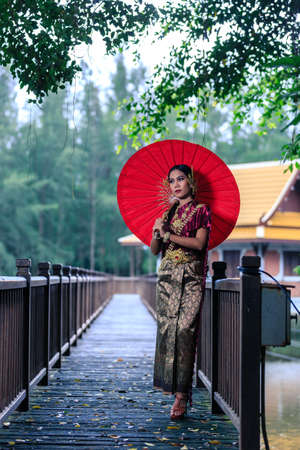 Beautiful Woman with Thai Traditional Dress King Rama posing at the bridgeの写真素材