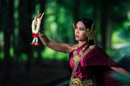 Beautiful Woman with Thai Traditional Dress King Rama dancing in the tropical forestの写真素材