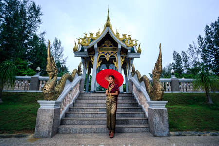 Beautiful Woman with Thai Traditional Dress King Rama posing near the templeの写真素材