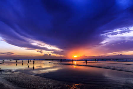 Magic Dramatic Unreal Sunset with people silhouettes in Kuta beach, Bali, Indonesiaの写真素材