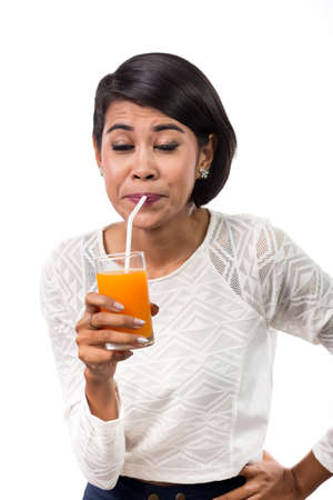 Beautiful asian woman drinking orange juice with funny emotion,  isolated on white background