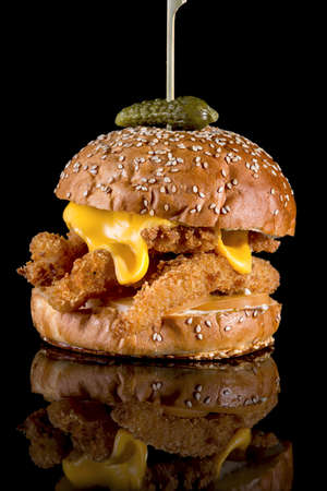 King Fisher Burger - Breaded fish filets, American cheese slice and tartar sauce with reflection isolated on black backgroundの写真素材