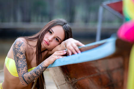 Close-up portrait of beautiful young woman near to old fishing boatの写真素材