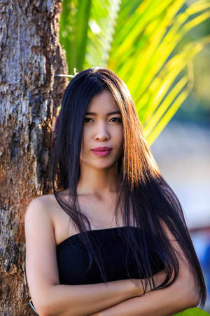 Close-up portrait young beautiful Asian girl with palm treeの写真素材