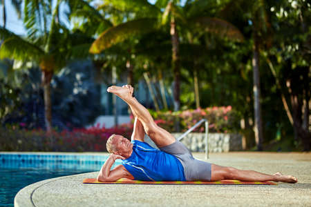 A man practice yoga at resort near to swimming poolの写真素材
