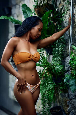 Beautiful asian sportive woman in bikini enjoying posing in the shower outdoor