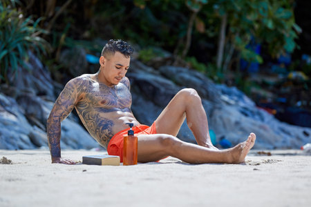 Athletic tattooed guy enjoying sunny morning on the sand at the tropical beach
