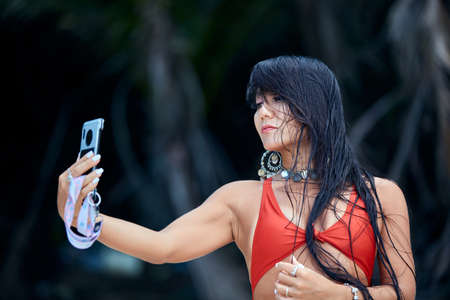 Close-Up lifestyle portrait of young hispanic woman doing selfie at the tropical nature. Blurred...