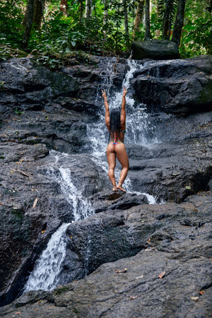 Young beautiful woman posing at small tropical waterfallの写真素材