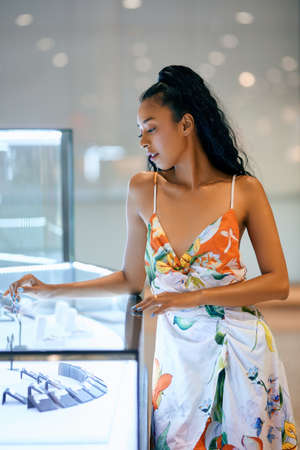 Shopping. Beautiful young asian woman looking at jewelry in showcase during shopping