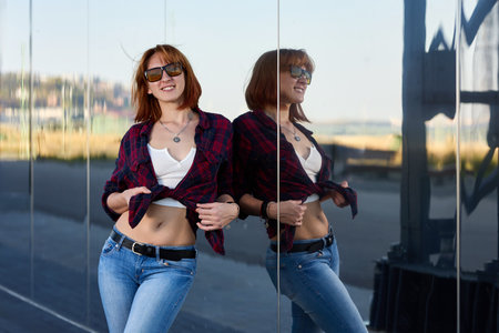 A fashionable redhead woman enjoying an autumn evening in the city. She's wearing a trendy red...