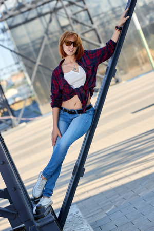A fashionable redhead woman enjoying an autumn evening in the city. She's wearing a trendy red jacket, a white t-shirt, and denim jeans, making a bold fashion statementの写真素材