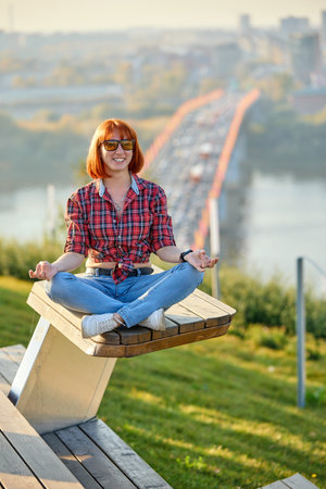 A fashionable redhead woman enjoying an autumn evening in the city. She's wearing a trendy red shirt, and denim jeans, making a bold fashion statementの写真素材