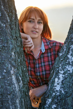A redhead woman poses gracefully in the warm glow of an autumn sunset. Smilingの写真素材