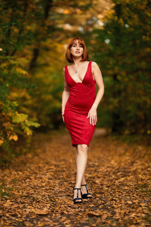 A redhead woman poses gracefully in the warm glow of an autumn sunset. Perfect for capturing the magic of fall and the beauty of the season.の写真素材