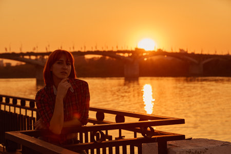 Close-up portrait of a young girl in the sunlight. City, Bridge. Sunset. Riverの写真素材